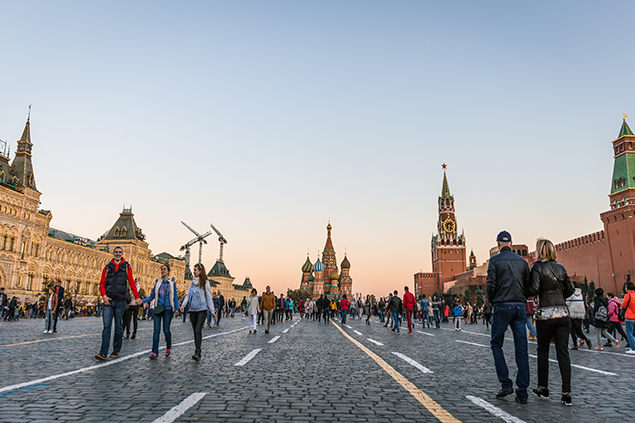 Tourists walk around historical Red Square surrounded by Gum, Saint Basil’s Cathedral and Kremlin Palace.