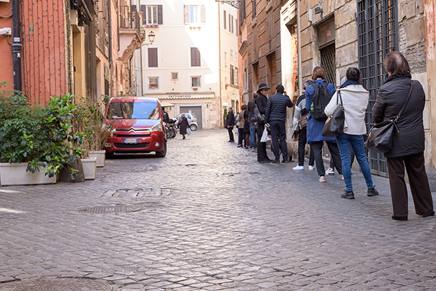 ROME, ITALY - 12 March 2020: Customers line up outside of a local supermarket in central Rome, Italy. Only a few persons can enter at a time, and shall maintain a 1-metre distance, by government decree.