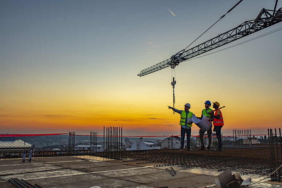 Multi ethic workers talking at construction site reviewing plans