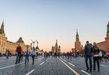Tourists walk around historical Red Square surrounded by Gum, Saint Basil’s Cathedral and Kremlin Palace.