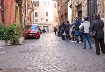 ROME, ITALY - 12 March 2020: Customers line up outside of a local supermarket in central Rome, Italy. Only a few persons can enter at a time, and shall maintain a 1-metre distance, by government decree.